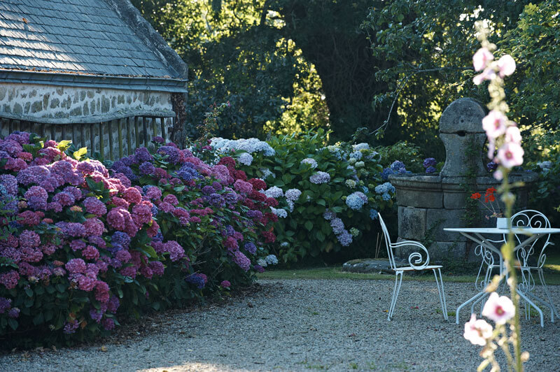 Jardin ferme de kerscuntec chaises et table en fer blanc fontaine en pierre hortensias