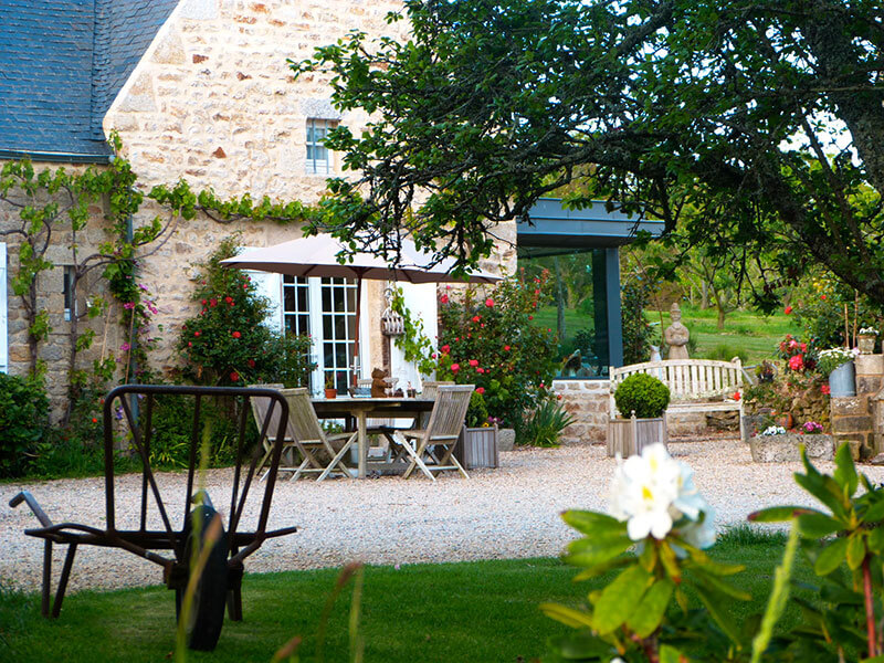 Vue extérieure de la ferme de Kerscuntec table et chaises lierre pelouse cadre verdoyant